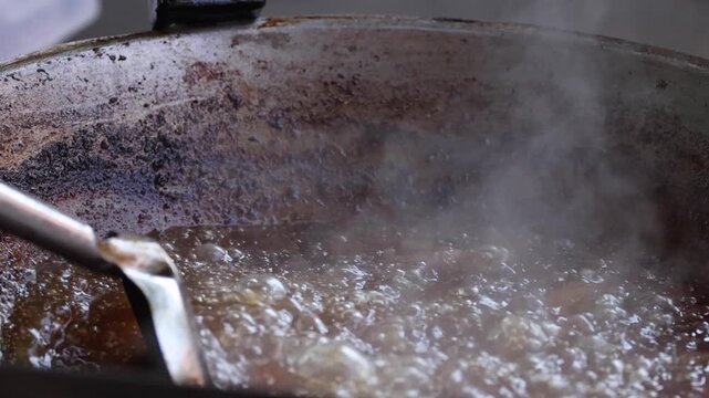Close Up of Meat Sizzling in Hot Oil Inside a Wok