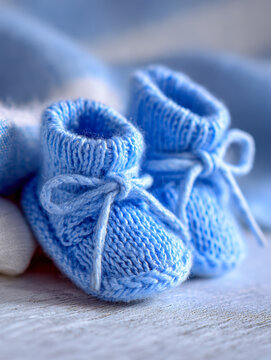 Soft knitted baby booties in pastel blue with delicate laces sitting on rustic wooden surface for newborn essentials and cozy infant wear concepts