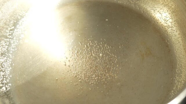 Tiny air bubbles cling to the bottom and sides of the pan, especially in the center, sparkling in the light.