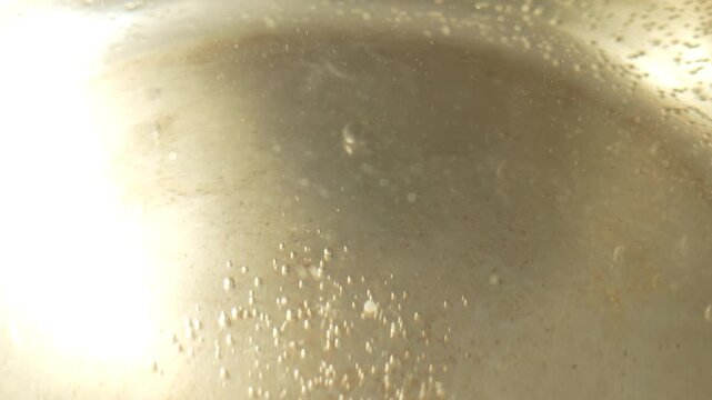 Tiny air bubbles cling to the bottom and sides of the pan, especially in the center, sparkling in the light.