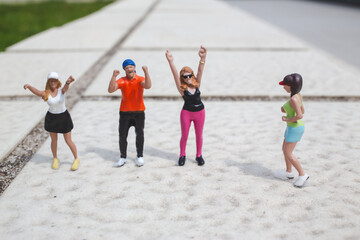 Fototapeta premium Miniature dancers raise arms energetically on outdoor concrete surface