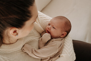 a mother holds a baby in her arms, a baby in her mother's arms, a mother and a newborn child, maternal love and care