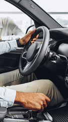 Driver holds steering wheel inside a modern car in an urban setting during the day