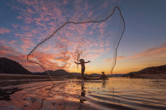 Silhouetted Laguna fisherman casts net at sunset