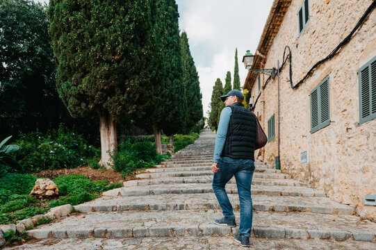 Man walking up El Calvari steps lined with cypress trees in Pollen&ccedil;a