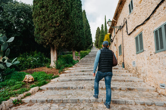 Man ascending El Calvari steps lined with cypress trees in Pollen&ccedil;a