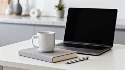 Modern home office setup with laptop, book, mug, and pen on a clean white desk