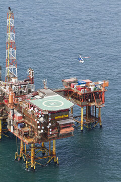 United Kingdom, United Kingdom - 15 February 2026: Aerial view of the oil rig platform in the vast, deep blue sea, with a helicopter approaching.
