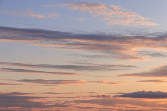 Sunset cloudscape with soft peach and lavender streaks across open sky, calm pastel tones layered clouds and wide copy space for background use in creative projects