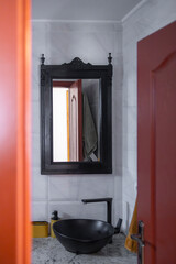 A bathroom interior with a rustic mirror and a modern sink.