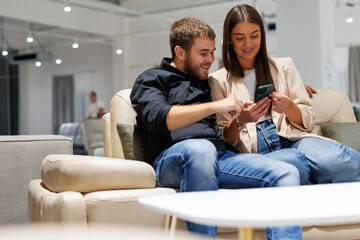 Couple shopping furniture using smartphone in store