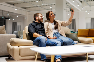 Couple taking selfie in furniture showroom looking for sofa