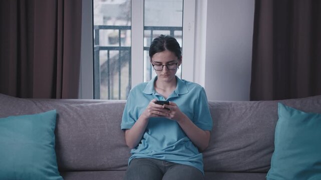 Evening Scene: Teenage Girl on the Sofa, Intensely Engaged in a Text Conversation on Her Mobile Device