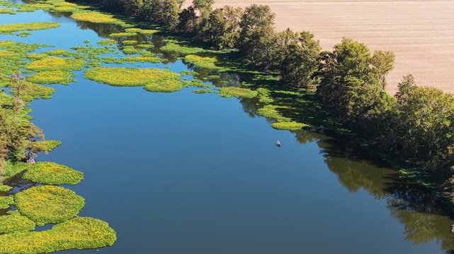 Aerial tilt up pullback from two fishermen on lake beside wooded bank, Noble Lake Pine Bluff Arkansas