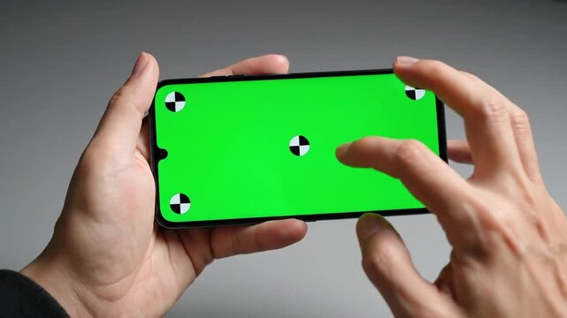 Hand holding smartphone with green screen for testing graphics at home