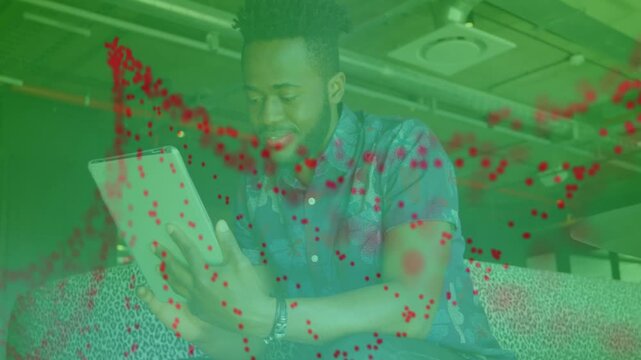 Adult man holding tablet on couch, red dots appearing forming overlay over him showing tech data