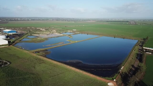 Comprehensive drone panorama showcasing a series of large water collection basins in Larache. Captures the geometric beauty of the reservoirs against an infinite backdrop of green fields.