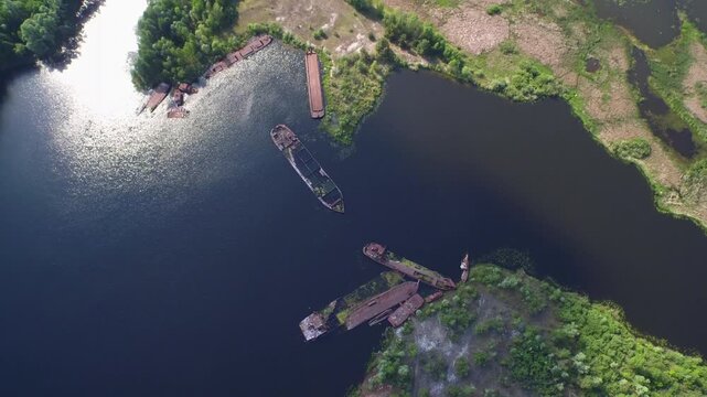 Aerial view of decaying, radioactive ships in Chernobyl Ship Graveyard, Ukraine; rusting vessels sit in the water.