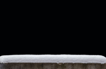 A snow hat on a rustic wooden table against a black background.