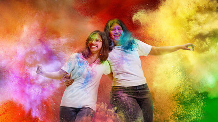 Two friends laughing in colorful Holi powder cloud. Concept of joyful festival atmosphere, vibrant...