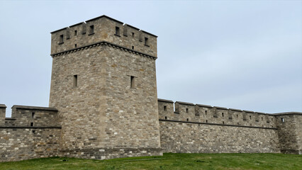 Medieval Stone Tower And Fortified Castle Wall Structure With Grassy Field