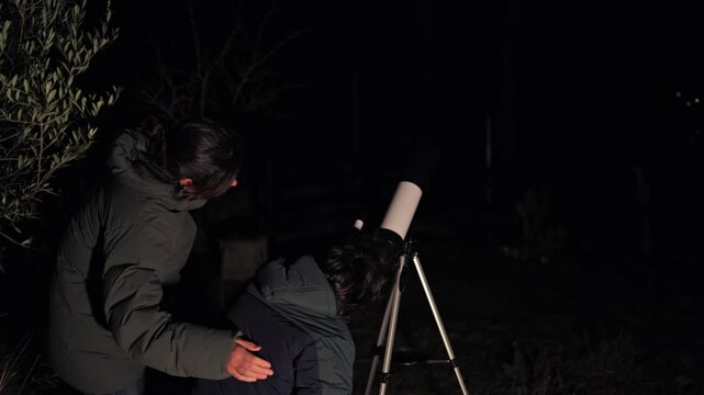 Mother and child looking through a telescope at the stars in a dark night, enjoying a bonding astronomical discovery and quality time together outdoors in the backyard