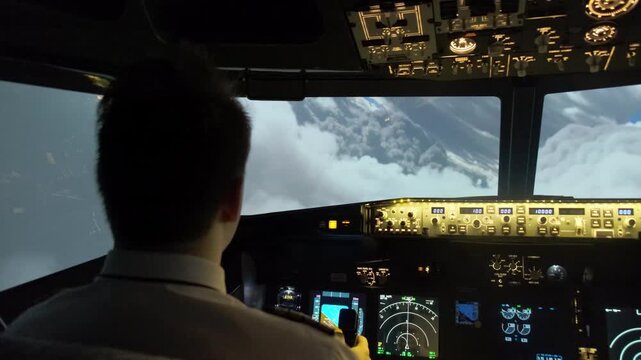 Male captain navigates airplane flying in poor visibility conditions due to dense clouds. Pilot holds steering wheel making maneuver