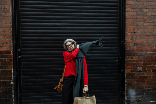 Stylish woman with red sweater and scarf shopping in urban city
