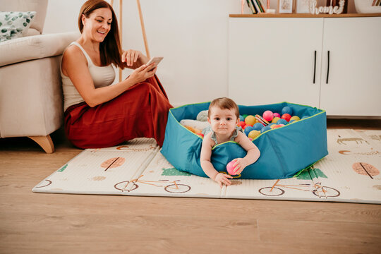 Mother and baby playing with pool balls at home in the living room