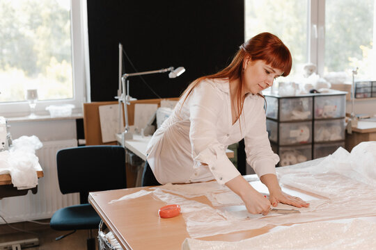Fashion designer drawing pattern for wedding dress in atelier