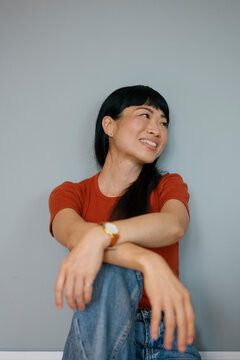 Smiling woman in casual outfit sitting indoors with relaxed expression