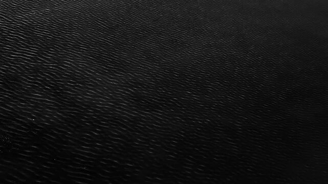 Extremely dark abstract close up texture showing the gentle movement of small water ripples.