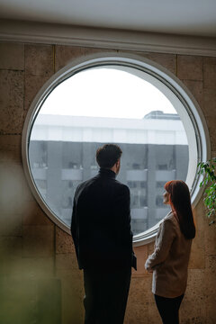 Business people in loft office looking thoughtfully out large round window