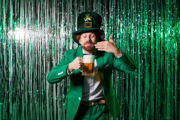 Leprechaun in classic suit holds glass of fresh beer close to nose, enjoying aroma and savoring...
