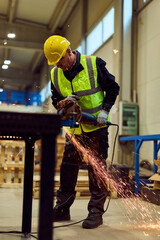 Naklejka premium Industrial Worker Grinding Metal in Workshop With Safety Vest and Hard Hat Creating Sparks