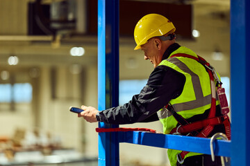 Construction Worker Wearing Safety Harness and Helmet Inspecting Industrial Site From Scaffolding © bnenin