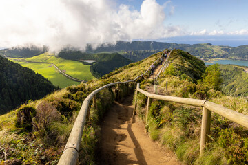 Naklejka premium A group of people are walking on a path that leads to a lake at Sete Cidades, Azores