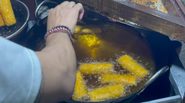 Frying traditional indonesian snacks risoles and pastel in a large wok with boiling oil