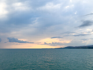 Obraz premium Sunset at Issyk Kul Lake in Kyrgyzstan. Bright sun breaking through clouds reflecting in clear turquoise water.