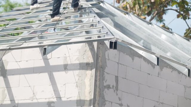 Steel roof frame installed on concrete block wall of unfinished building. Residential construction site, structural engineering and housing development concept.