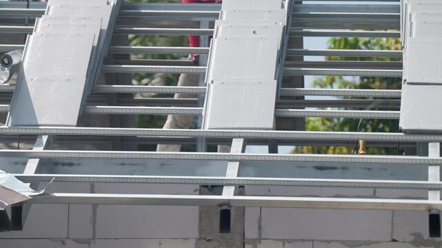 Lightweight concrete blocks installed on steel roof frame at residential construction site. Modern building system, structural engineering and housing development concept.