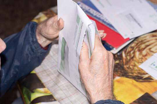 Elderly man opening an electricity bill from the Spanish energy company Iberdrola. Senior household expenses and financial responsibility concept