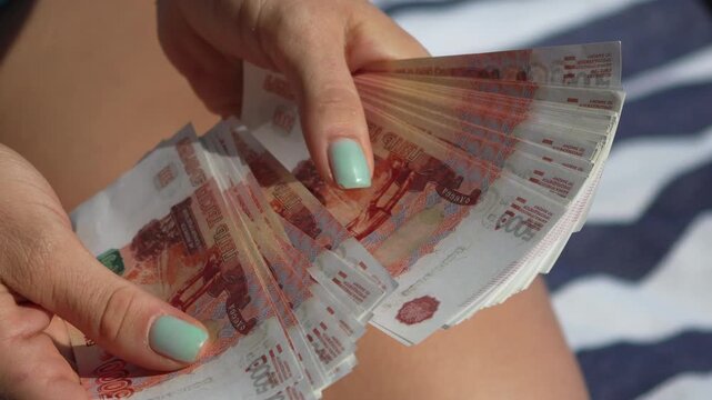 Rubles, counting, money: Female hands counting a stack of Russian 5000 ruble banknotes, close-up.