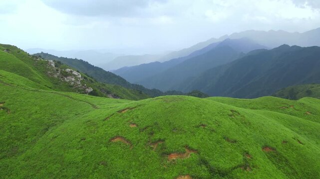 Drone flying forward above rolling green peaks in Wugong Mountain