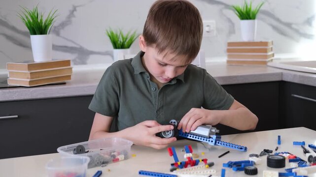 boy builds a toy robot car using his imagination. Robotics, children's technology, robot construction kit, educational toy.