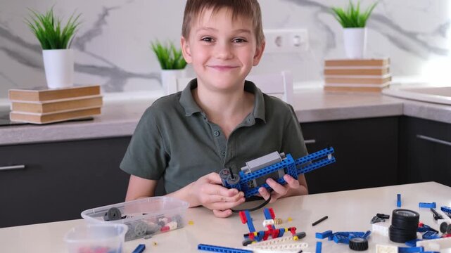 boy builds a toy robot car using his imagination. Robotics, children's technology, robot construction kit, educational toy.