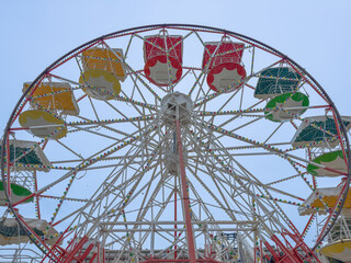 Empty ferris wheel stands still in luna park during daytime hours.