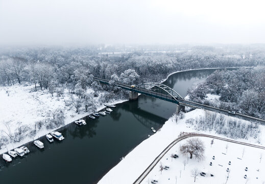 Pancevo, Serbia - January 05 2026: Tamis river in the winter. River in the winter with snow. Boats, bridge. Aerial view. Drone shot.