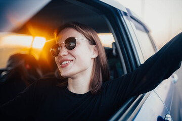 A positive female driver is driving a car and smiling with delight