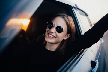 A positive female driver is driving a car and smiling with delight